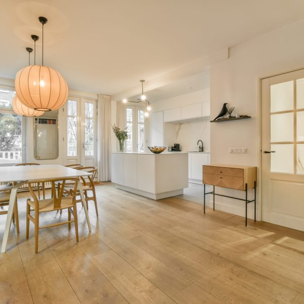 a dining room with wood flooring and an open door leading out to the kitchen, living room and dining area