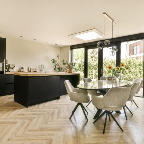a kitchen and dining area in a modern home with wood flooring, white walls and black cabinetry on either side
