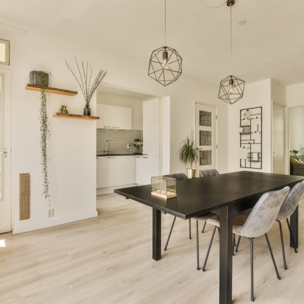 a dining room with white walls and wood flooring in the center of the room, there is a large black table surrounded by