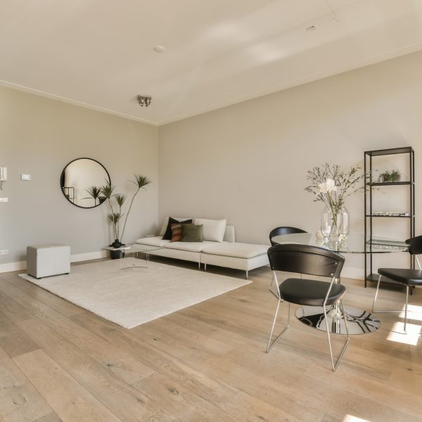a living room with white walls and wood flooring in the center of the room is a large round mirror on the wall