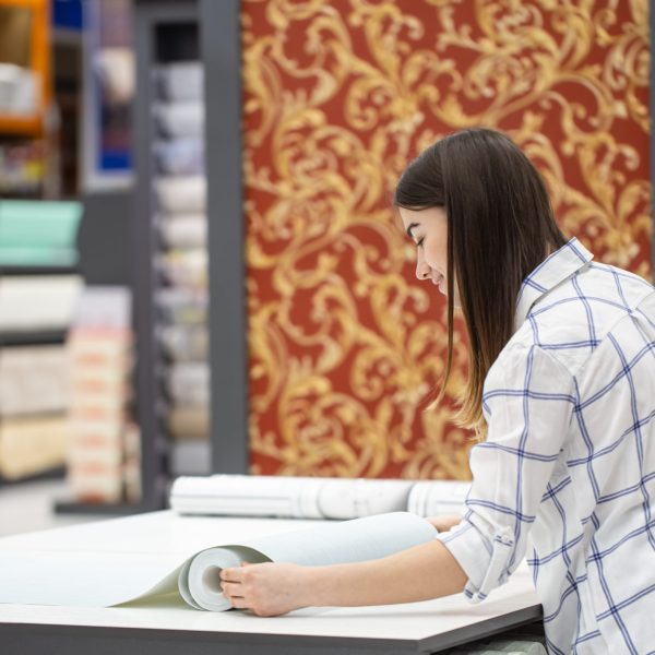 A young woman in a store chooses Wallpaper for her home. Concept of repair and shopping.