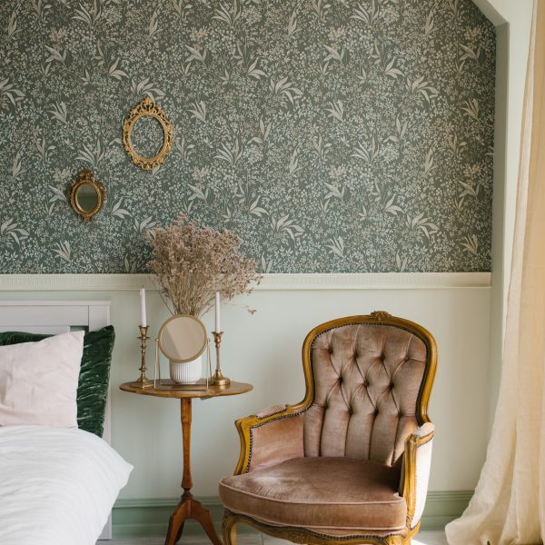 Classic bedroom interior. A brown armchair by the window and the bed and the bedside table with a mirror and candles on it