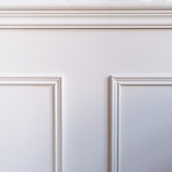 Classic wainscot wood decoration detail. Retro white wooden wall panel background, closeup view. Interior room architecture design